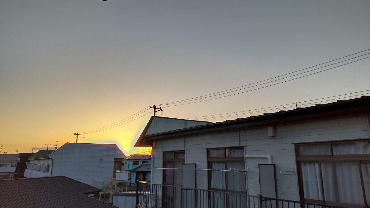 屋根屋根の間から、静かに沈む太陽。